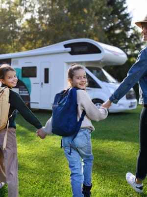 rear-view-of-young-family-with-backpacks-going-to-rv